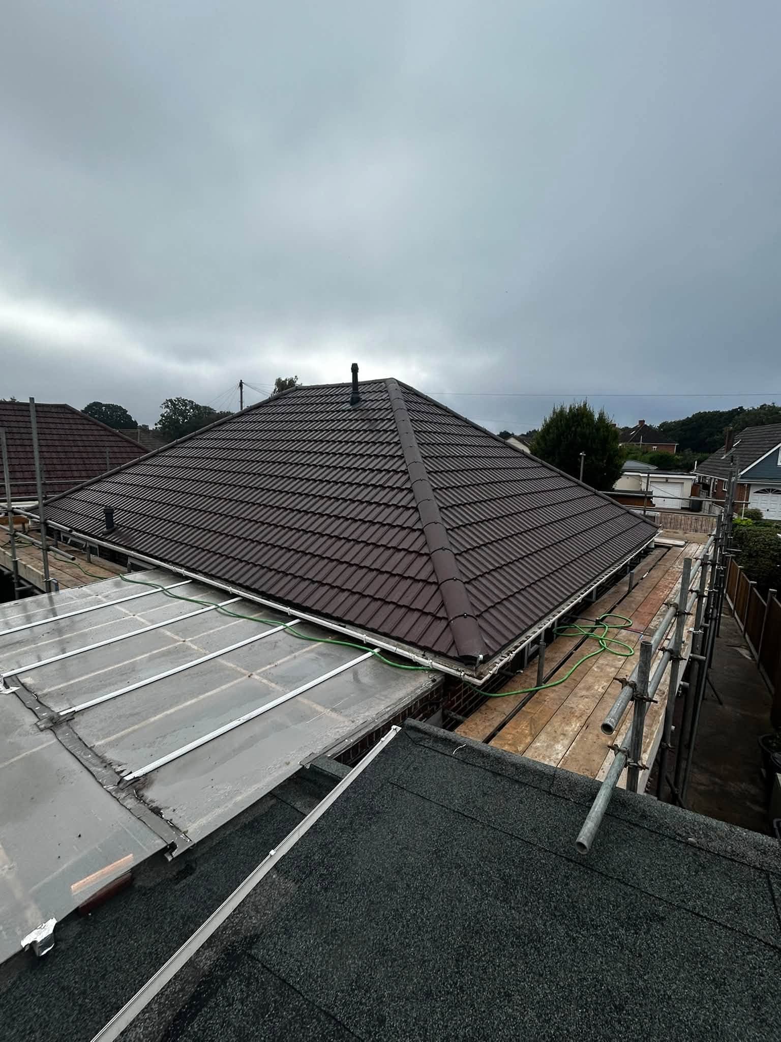 Tiled roof replacement: a finished dark brown tiled hipped roof in Kinson